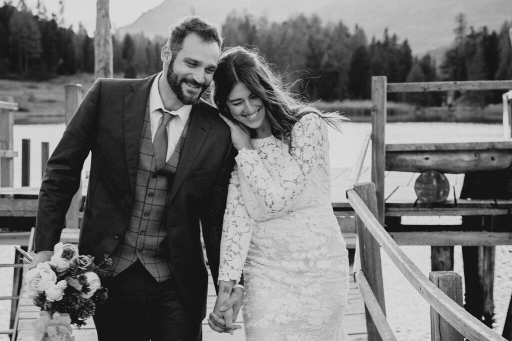 Brautpaar bei einer eleganten Hochzeit in St. Moritz – inniger Moment auf einer Holzbrücke in den Schweizer Alpen, fotografiert in zeitlosem Schwarzweiss.
